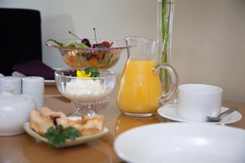 uma mesa com uma taça de fruta e um jarro de sumo de laranja em Tairoa Lodge em Hawera