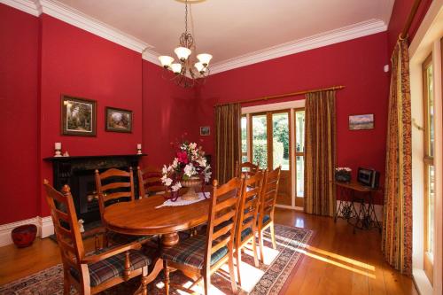 a dining room with red walls and a wooden table and chairs at Tairoa Lodge in Hawera