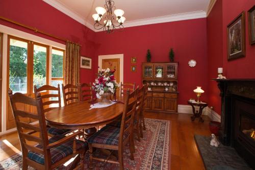a dining room with red walls and a table and chairs at Tairoa Lodge in Hawera