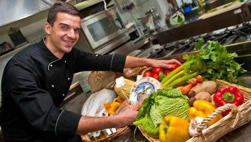 a man in a kitchen with a bunch of vegetables at Agriturismo Gattogiallo in Montegabbione