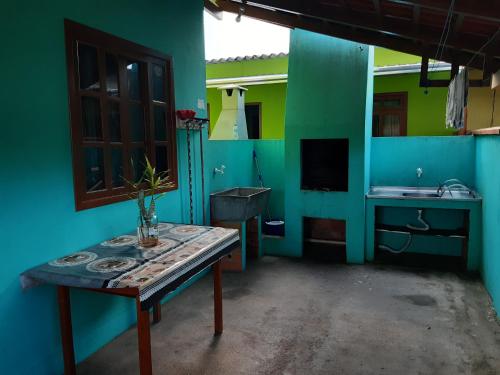 cocina azul y verde con mesa y fregadero en JOÃO CARLOS CASAS 3 Quartos Penha SC, en Penha
