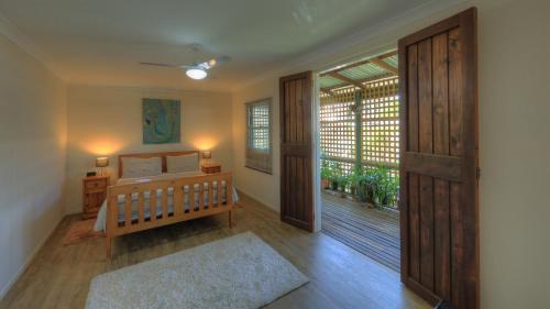 a bedroom with a bed and a sliding glass door at Village Stays Coldstream Gallery Bungalow in Ulmarra
