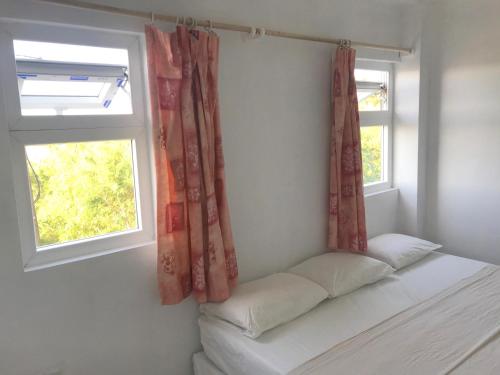 a bed in a room with two windows at Cleopatra Villas - Sea View in Rodney Bay Village