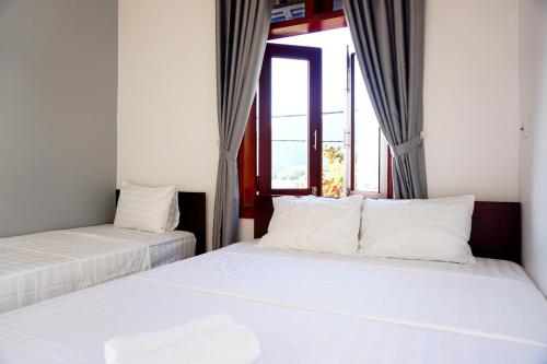 two beds in a room with a window at Monkey Homestay & Bar in Tân Hiệp
