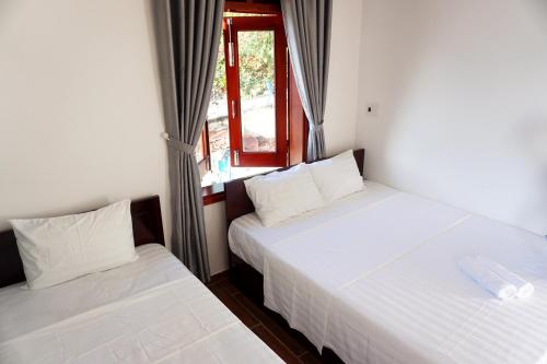 two beds in a room with a window at Monkey Homestay & Bar in Tân Hiệp