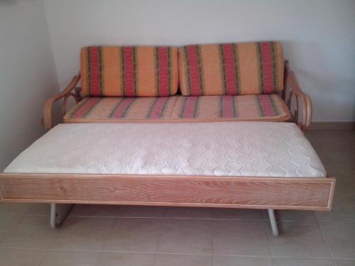 um banco de madeira sentado no canto de uma sala em Albufeira 1 bedroom apartment 5 min. from Falesia beach and close to center! L em Albufeira