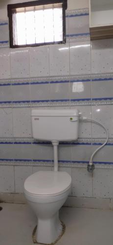 a bathroom with a white toilet and a window at LN BEACH Homestay in Puri