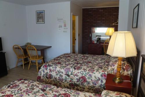 a bedroom with a bed with a lamp and a table at Aberdeen Motel in Whycocomagh