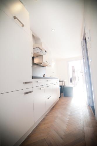 a kitchen with white cabinets and a wooden floor at Apartment De Maasnacht in Maaseik