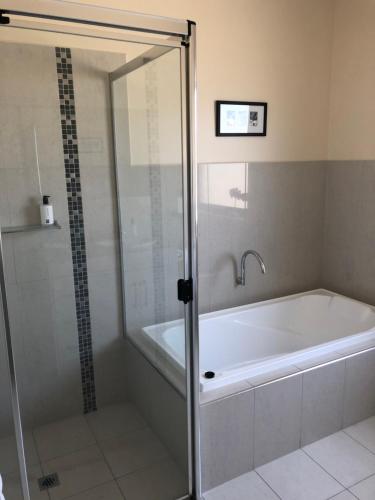 a bathroom with a tub and a glass shower door at Residence On Robe in Robe