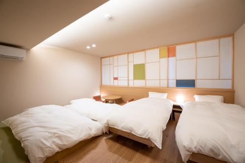 dwa łóżka w pokoju z białą pościelą w obiekcie marutto Ishikawa w mieście Kanazawa