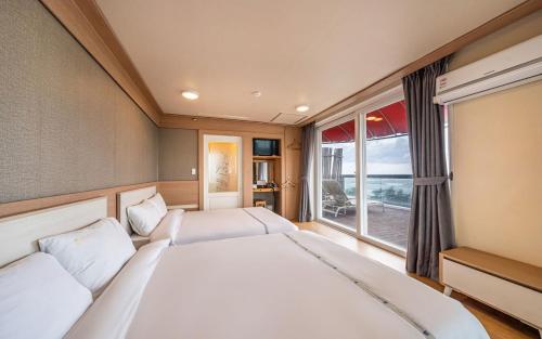 a bedroom with two beds and a large window at BENIKEA San&Bada Jumunjin Resort in Gangneung