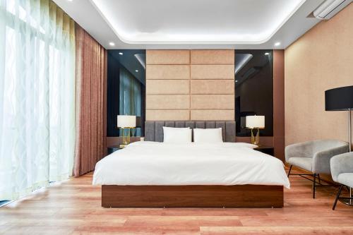 een slaapkamer met een groot bed en 2 stoelen bij BBQ Hostel Ha Long 2 in Ha Long