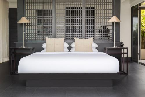 a bedroom with a large white bed with two lamps at The Pavilions Phuket in Bang Tao Beach