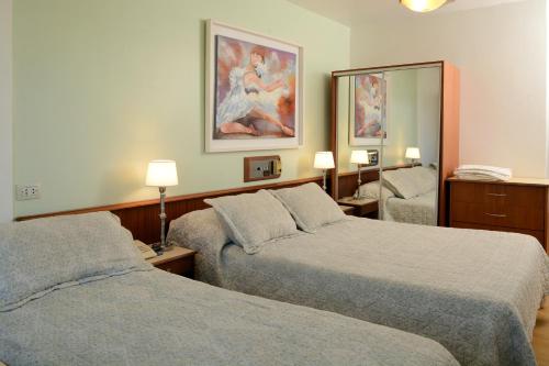 Habitación de hotel con 2 camas y espejo en Hotel Capvio en Villa Carlos Paz