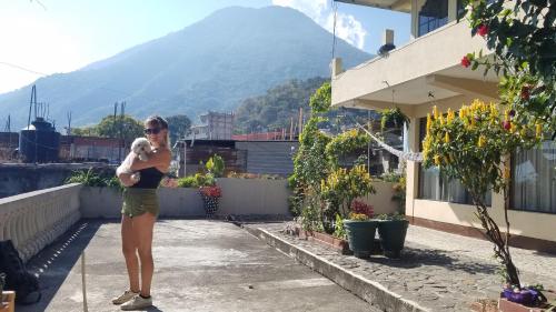 a woman standing on a balcony with a dog at Casa Guillermo Batz in San Pedro La Laguna