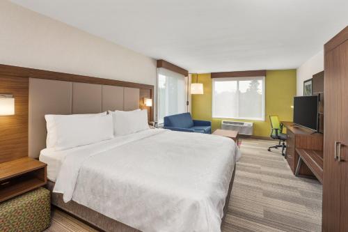 a hotel room with a large bed and a television at Holiday Inn Express & Suites Tacoma by IHG in Tacoma