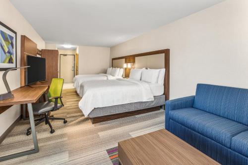 タコマにあるHoliday Inn Express & Suites Tacoma, an IHG Hotelのベッド、デスク、ソファが備わるホテルルームです。