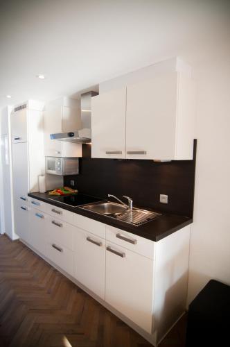 a kitchen with white cabinets and a sink at Apartment De Maasnacht in Maaseik
