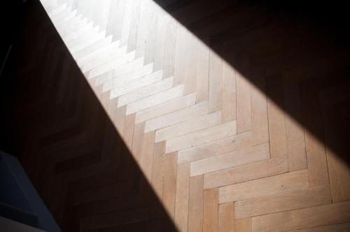 a shadow of a stairwell on a wooden floor at Apartment De Maasnacht in Maaseik