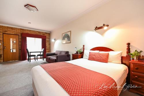 a hotel room with a bed and a dining room at Narrandera Club Motor Inn in Narrandera