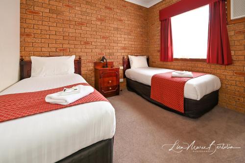 a room with two beds and a brick wall at Narrandera Club Motor Inn in Narrandera