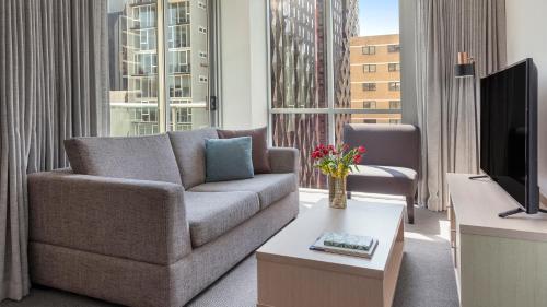 a living room with a couch and a tv at Oaks Brisbane Festival Suites in Brisbane