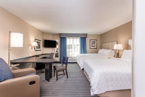 a hotel room with two beds and a desk at Candlewood Suites Eau Claire I-94 by IHG in Eau Claire