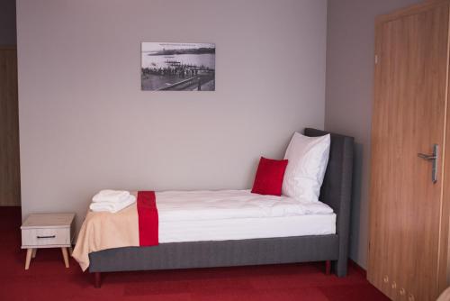 a bedroom with a bed with a red stripe on it at Zajazd u Piasta Kołodzieja in Kruszwica