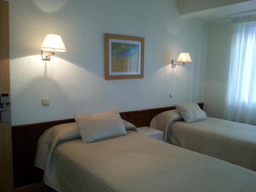 a hotel room with two beds and lights on the wall at Pensión Lizaso in Irún