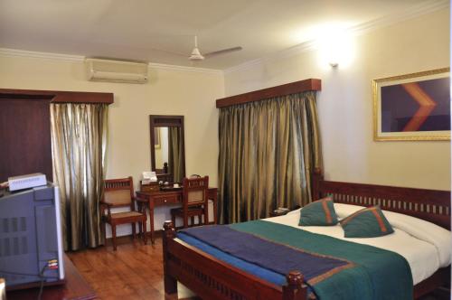 Pokój hotelowy z łóżkiem, biurkiem i pokojem w obiekcie Niketana @ Boat Club w mieście Ćennaj