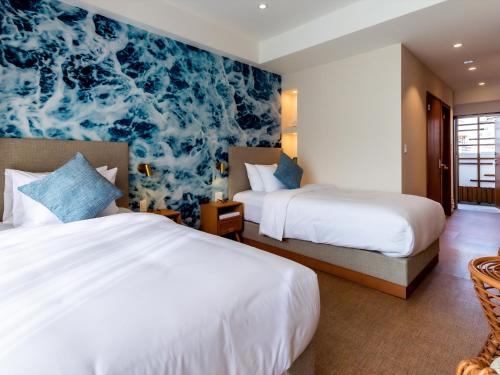 a bedroom with two beds and a blue and white wallpaper at The Moana by DSH Resorts in Chatan