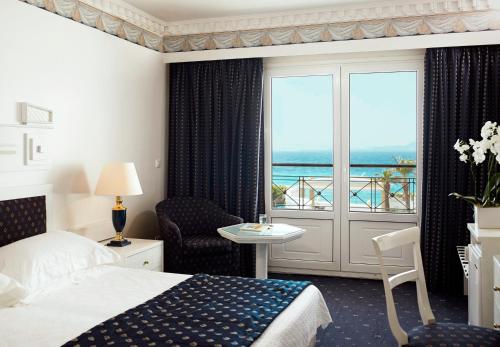 Cette chambre d'hôtel comprend un lit et offre une vue sur l'océan. dans l'établissement Mitsis Grand Hotel, à Rhodes