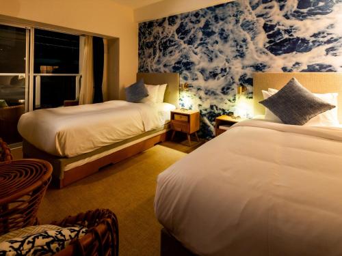 a hotel room with two beds and a blue and white wallpaper at The Moana by DSH Resorts in Chatan