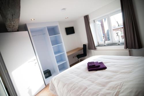 a bedroom with a white bed with a purple towel on it at Apartment De Maasnacht in Maaseik