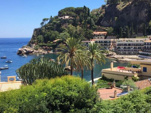 a group of buildings and palm trees next to the ocean at DHOME Baia Mazzaro' in Taormina