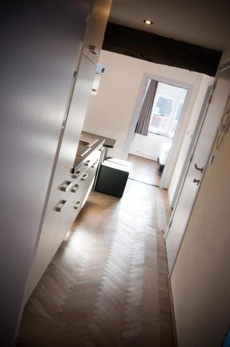 a kitchen with white cabinets and a hallway with a window at Apartment De Maasnacht in Maaseik