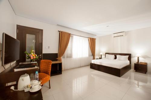 a bedroom with a bed and a desk and a television at The Radiant Hotel in Kuta