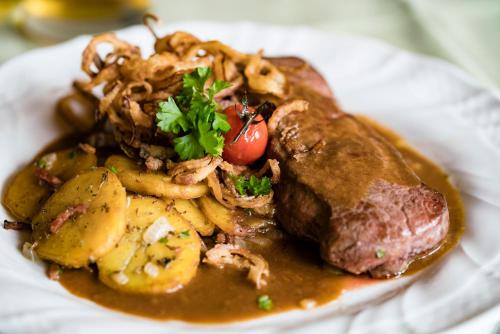 un plato de comida con carne y patatas en un plato en Hotel Bayernhof en Greding