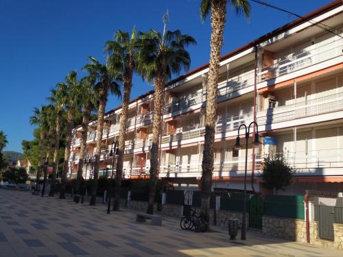 ein Gebäude mit Palmen davor in der Unterkunft ENCANTADOR apartamento frente a la playa de Bara in Roda de Berà