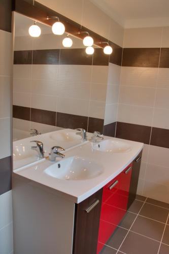 une salle de bain avec deux lavabos et un grand miroir dans l'établissement Gite de Villaine, à Theillay