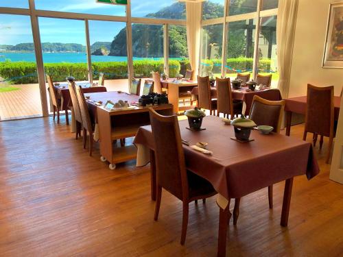 勝浦にあるホテルなぎさやのテーブルと椅子、大きな窓のあるレストラン
