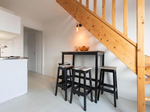 une cuisine avec une table et des tabourets sous un escalier dans l'établissement Duplex coquet avec PARKING proche centre-ville de Lyon, à Villeurbanne