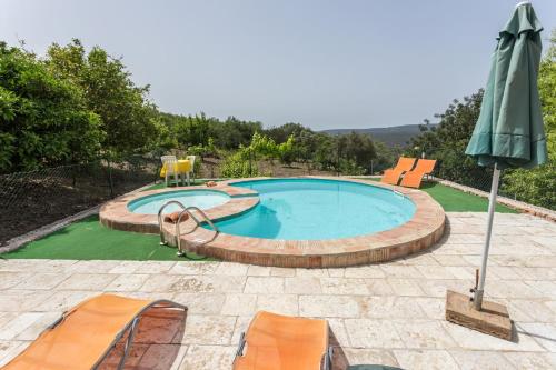 a swimming pool with chairs and an umbrella at Casa Amoreira - Quinta Amoreira in Faro
