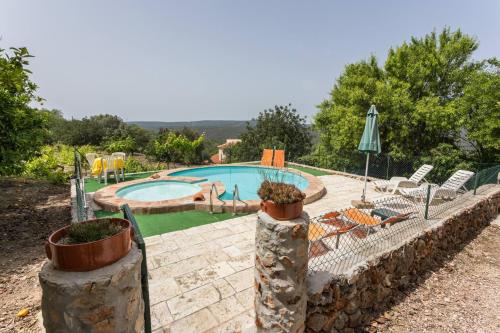 a swimming pool with chairs and an umbrella at Casa Amoreira - Quinta Amoreira in Faro