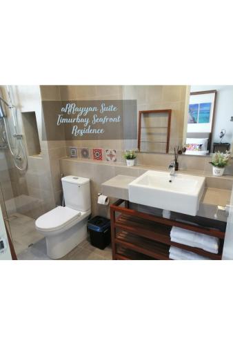 a bathroom with a white toilet and a sink at Timurbay Seafront Residence aRRayyan Suites in Kuantan