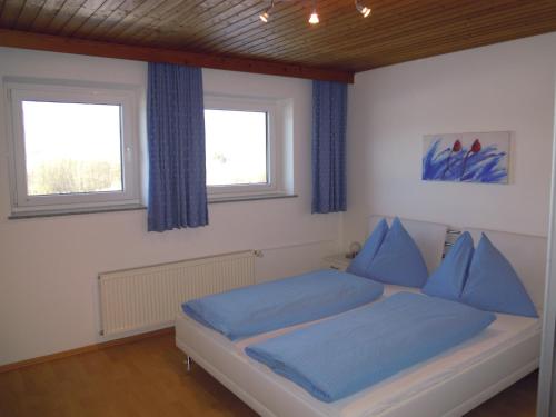 a bedroom with a bed with blue sheets and two windows at Ferienwohnungen Familie Jarnig Inge in Görtschach