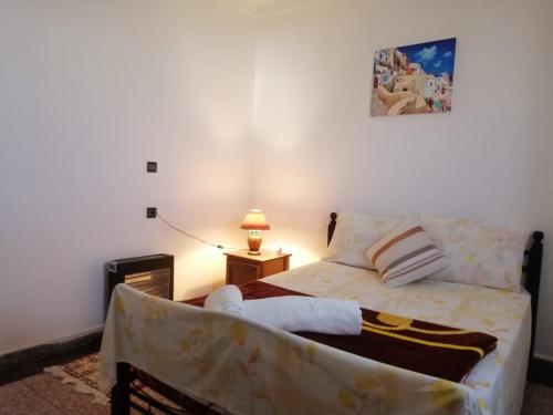 ein Schlafzimmer mit einem Bett und einem Tisch mit einer Lampe in der Unterkunft Chez Amel Guoumi in Oualidia