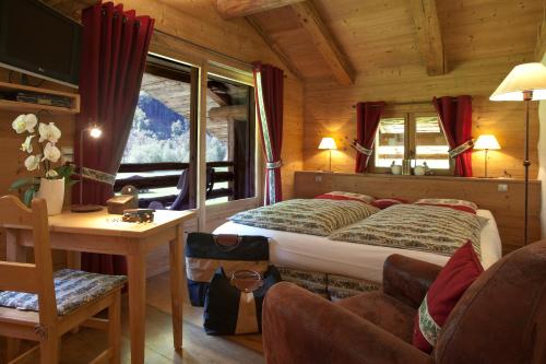 1 dormitorio con cama, mesa y sofá en Chalet-Hôtel Les Fermes de Pierre & Anna, en Le Grand-Bornand