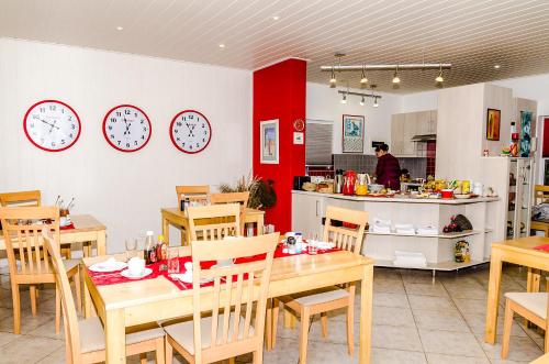 a restaurant with tables and clocks on the wall at Meike's Guesthouse in Swakopmund